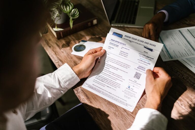 Persona revisando documento financiero en escritorio de madera